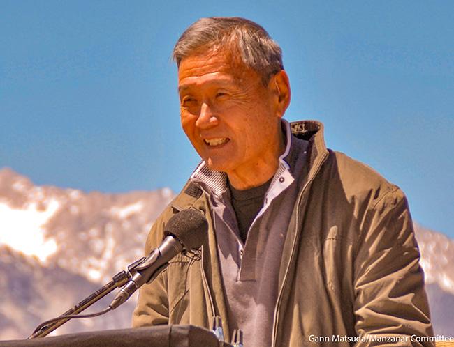 Alan Nishio speaks at a podium