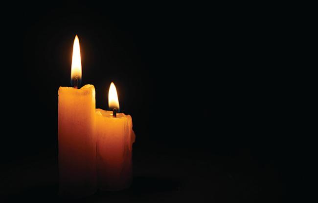Two candles are burning against a black background